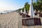 Row of folded beach umbrellas and sun loungers on a sandy beach by the sea