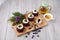 Row of four brown cakes with blue berry on top placing together violate flower, tea pot and berry