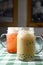 Row of fresh boba bubble tea glasses on wooden table with green plaid tablecloth background.