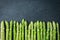Row of fresh raw green Asparagus on dark stone background. Organ