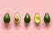 Row of fresh wholes and halves of organic avocado with kernels in center on pink backgrond. Top view