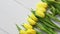 Row of fresh yellow tulips on white wooden table