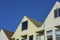 Row of gable house facades with wooden or timber exteriors and windows with clear blue sky background in late afternoon