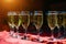 A row of glasses filled with cold champagne lined up, ready to be served. Glasses with Martini on the table - party background