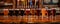 A row of glasses filled with various craft beers sits on a wooden bar counter.