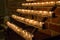 Row of glowing candles in church. Candles with flame on dark background. Faith and religion concept. Candles in catholic church.