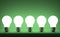 Row of glowing tungsten light bulbs on green