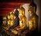 Row of golden and dark seated buddhas in a Buddhist temple