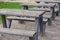 A row of gray benches and tables made of wood and metal