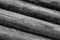 Row of gray round logs horizontal weathering surface cracked old rustic background base monochrome