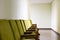 Row of Green Auditorium Seating Soft Chairs with Writing Pads Placed along the Wall in the Hallway. Business or Political Event,