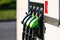 Row with green and black refueling guns at the gas station, close-up, horizontal shot