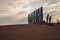 row of high ritual Buryat religious pillars tied with colored ribbons, against the background of a warm sunset sky in the Baikal