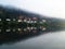 Row of Homes Reflects in River Water with Misty Sky