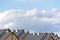 Row house roofs, condo rooftop panorama and bright summer clouds, panoramic roofscape sunny summer cloudscape