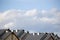 Row house roofs, condo rooftop panorama and bright summer clouds, panoramic roofscape sunny summer cloudscape