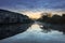 A row of houses surrounding a river filled with reflections of the houses at sunrise