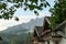 A row of houses with the view on high and sharp Dolomites in Italy. There is a dense forest between the houses