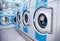 Row of industrial laundry machines in commercial laundromat. Concept business washer shop