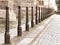 Row of iron pillars between cobbled street and pedestrian sidewalks