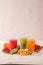 Row of kiwi, orange and water melon smoothie and various pieces of fruit over wooden background