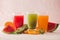 Row of kiwi, orange and water melon smoothie and various pieces of fruit over wooden background