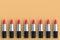 Row of lipsticks on beige background. Cosmetic accessories. Make-up tools. Top view. Copy space