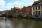 Row of medieval colored buildings along Lys River dutch: Leie Spring landscape photo. Selective focus with wide angle lens