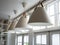 Row of modern beige round conical light lamps hanging from tall ceiling near the window in minimal style.