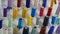 A row of multi-colored different threads for a sewing machine and overlock in a sewing workshop or atelier. Rows spools
