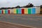 A row of multi coloured beach huts stands attractively by the main coast road in Exmouth, Devon