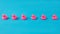 A row of neatly aligned pink plastic ducks against blue background. Minimal creative concept for summer holidays banner or