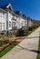 Row of new townhomes in a sidewalk neighborhood. On a sunny day in spring against bright blue sky.