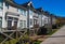 Row of new townhomes in a sidewalk neighborhood. On a sunny day in spring against bright blue sky.