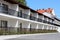 Row of newly built motel room balconies with black metal fences surrounded with decorative garden plants and concrete tiles