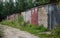 Row of old brick garages with metal gates on a dirt road