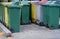 Row of old green and yellow and gray trash bin in the community,