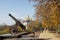 Row of old iron cannons stand on pedestals in autumnal park