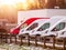 Row one red and many white commercial vans in a dealership for sale or rent in a snow. Cold winter season. warm sun flare. Used