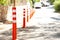 A row of orange bollards with reflective stripes near a stone fence