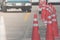 Row of orange traffic cones setting on roadway beside parking lot.