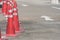 Row of orange traffic cones setting on roadway beside parking lot.