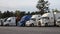 A row of parked semi trucks at a truck stop pan right