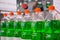 Row of pet bottles with green lemonade on conveyor belt - close up