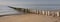 row of poles on beach of zeeland in the netherlands under blue sky in spring