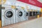 A row of qualified coin-operated washing machines in a public store.