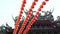 Row of red Chinese paper lanterns with ornate gold patterns and tassels. hanging on wires outside. Shot on the sky background at B