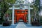 Row of red torii gates with two stone statues of guardian foxes on the sides in Suwa Shinto Shrine in Nagasaki, Japan.