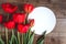 Row of red tulips on wooden background with space for message. Women`s or Mother`s Day background. Top view