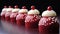 A row of red velvet cupcakes with white frosting and a cherry on top